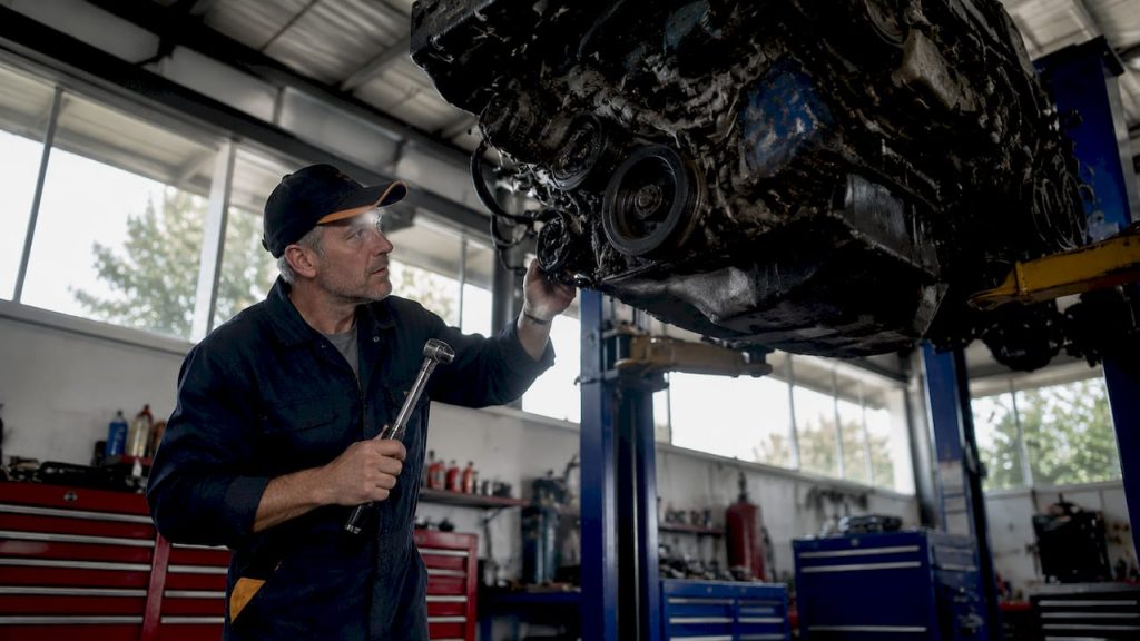 Mechanic inspecting car engine in workshop